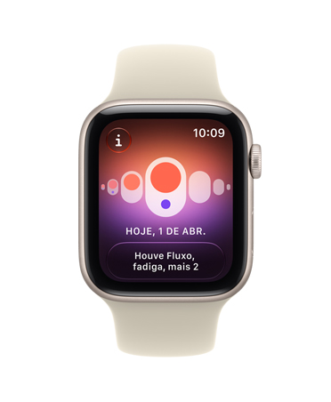 Apple Watch SE 3 com caixa estelar de alumínio e pulseira esportiva na cor areia (bege-pálido). A tela mostra o monitoramento da saúde (Acompanhamento de Ciclo). Na lateral direita, a Digital Crown.