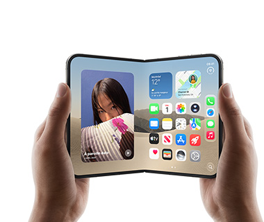 Deux mains tiennent un iPhone Duo ouvert, l’écran de gauche affiche la photo d’une femme, l’écran de droite affiche un écran d’accueil avec plusieurs icônes d’apps, dont Messages, Photos, Caméra et App Store