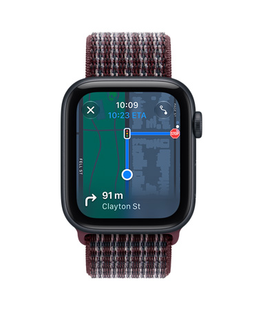 Apple Watch SE 3, hliníkové pouzdro, temně inkoustová barva, na obrazovce aplikace Najít (s memoji na pozadí mapy), na pravém boku korunka Digital Crown, provlékací sportovní řemínek, burgundská kostkovaná barva