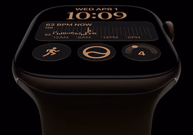 Apple Watch Series 12 med urkasse av aluminium i fargen mørk bronse og Sport Band i fargen oliven. Skjermen viser Modulær-urskiven med komplikasjoner for dag og dato, Treningsøkter, Aktivitetsringer og Musikk. På høyre side av urkassen vises Digital Crown.