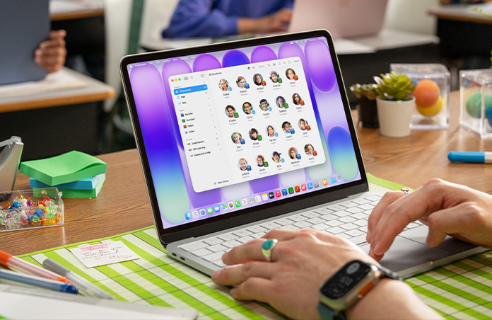 Seorang guru sedang duduk dengan Mac yang terbuka, dan aplikasi Classroom menampilkan daftar siswa lengkap di layar