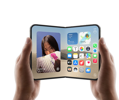 열려 있는 iPhone Duo를 양손으로 잡고 있는 모습. 왼쪽 화면에는 한 여성의 사진이, 오른쪽 화면에는 메시지, 사진, 카메라, App Store 등 다양한 앱 아이콘이 있는 홈 화면이 표시되어 있습니다.