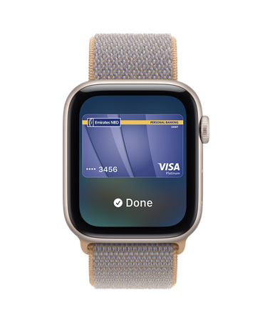 Apple Watch SE 3, aluminum case, starlight color, screen shows Wallet, payment card graphic, right side exterior, Digital Crown dial, Sport Loop band, chambray blue color (light blue-gray)