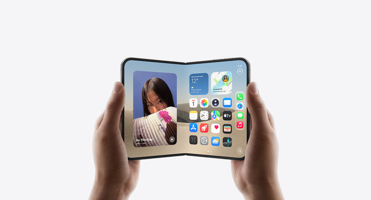 جهاز iPhone Duo، يدان تحملان الجهاز في الوضع الأفقي وهو مفتوح، الجهة الخارجية للشاشة الداخلية، لون أبيض النجوم، واجهة الشاشة الرئيسية لنظام iOS، الصور في الجهة اليسرى، تطبيقات في الجهة اليمنى