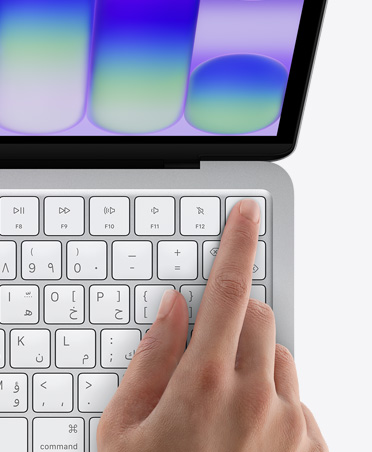 جهاز MacBook Neo، لون فضي، إصبع شخص على مستشعر بصمة الإصبع في الزاوية العلوية اليمنى من لوحة المفاتيح