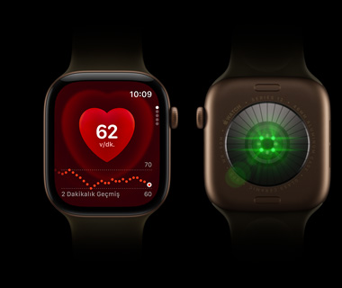 İki adet Apple Watch Series 12 yan yana duruyor; soldaki Apple Watch Series’in önden görünümü, ekranda kalp atış hızı takibi gösteriliyor; sağdaki Apple Watch Series 12’nin arkadan görünümü, yeşil renkte parlak ışıklar gösteriliyor