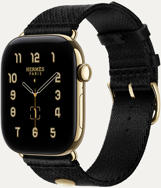 Apple Watch Hermès Series 12, Clou de Selle analog watch face (hour, minute, and second hands, complications: lunar phase, date), titanium case, radiant gold color, right side exterior, Digital Crown, side button, paired with Noir Satin Clou de Selle band, smooth black satin webbing with radiant gold hardware that matches the watch case