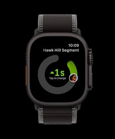 Apple Watch Ultra 3 med urkasse i sort titanium, appen Strava, der viser træningstyperne løb udendørs, cykling udendørs og løb indendørs, og Trail Loop-rem i sort/koksgrå