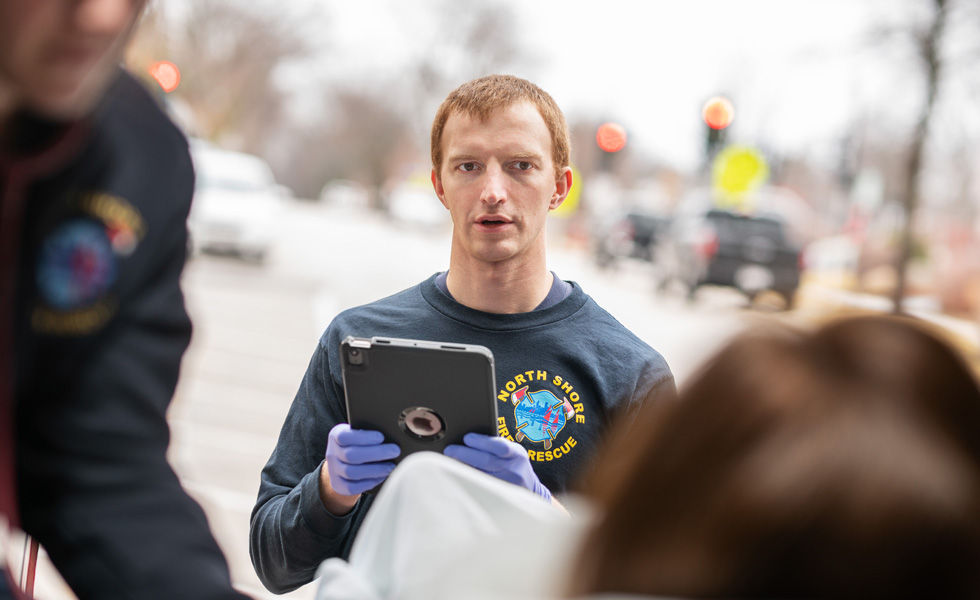 Un membre du personnel tient un iPad à la main et parle à une patiente allongée dans un véhicule de transport médicalisé