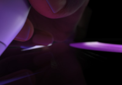 En bruger holder Apple Pencil Pro i skriveposition. Spidsen presses ned på en skærm, hvor der tegnes tykke strøg i neonlilla.