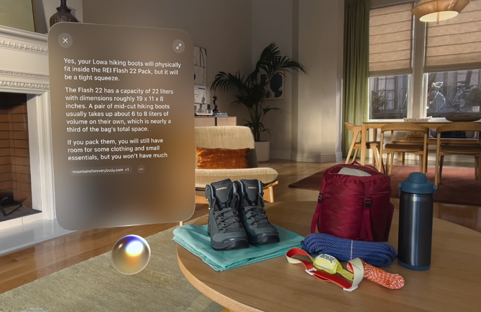 Answer to a query for Siri about packing camping essentials hovers above Siri Orb on left side of screen, hiking boots, ropes, backpack, water bottle, and head lamp sit on table on right side of screen